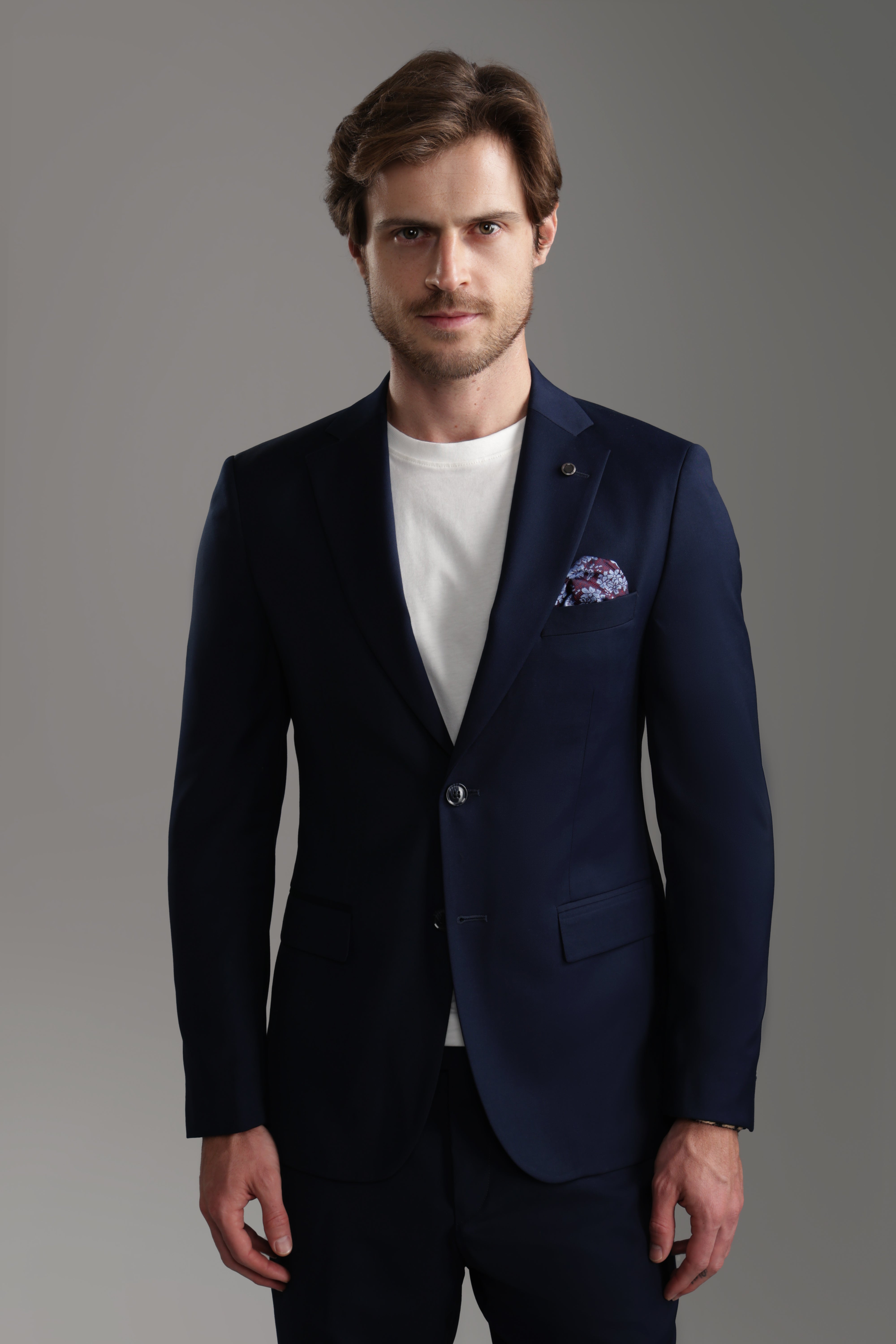 Navy suit jacket featuring a tailored fit, worn by a man with a white shirt, showcasing a sophisticated look.